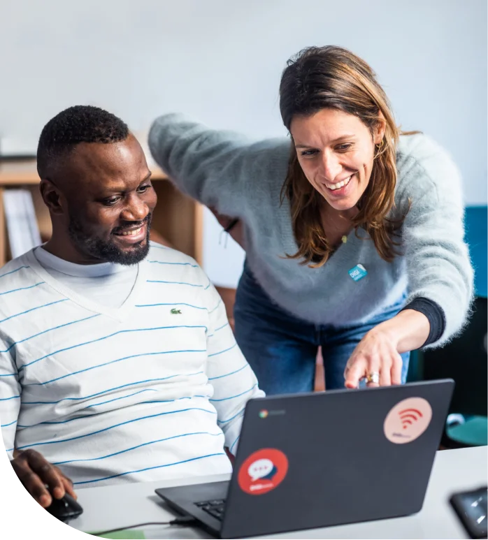 Een lesgever helpt een cursist aan een laptop tijdens een computerles van Oostende@internet